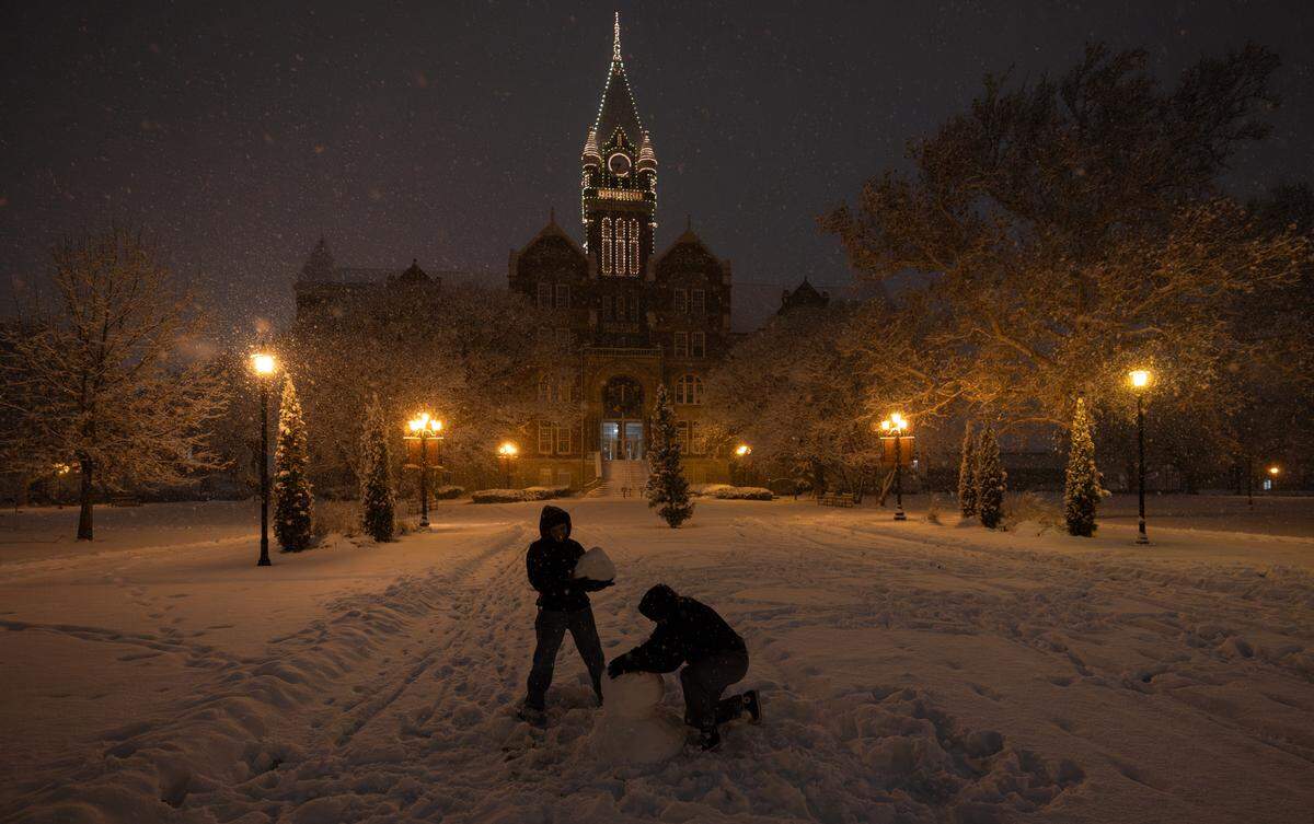 Two students work on a snowman at Friends University on Thursday night.