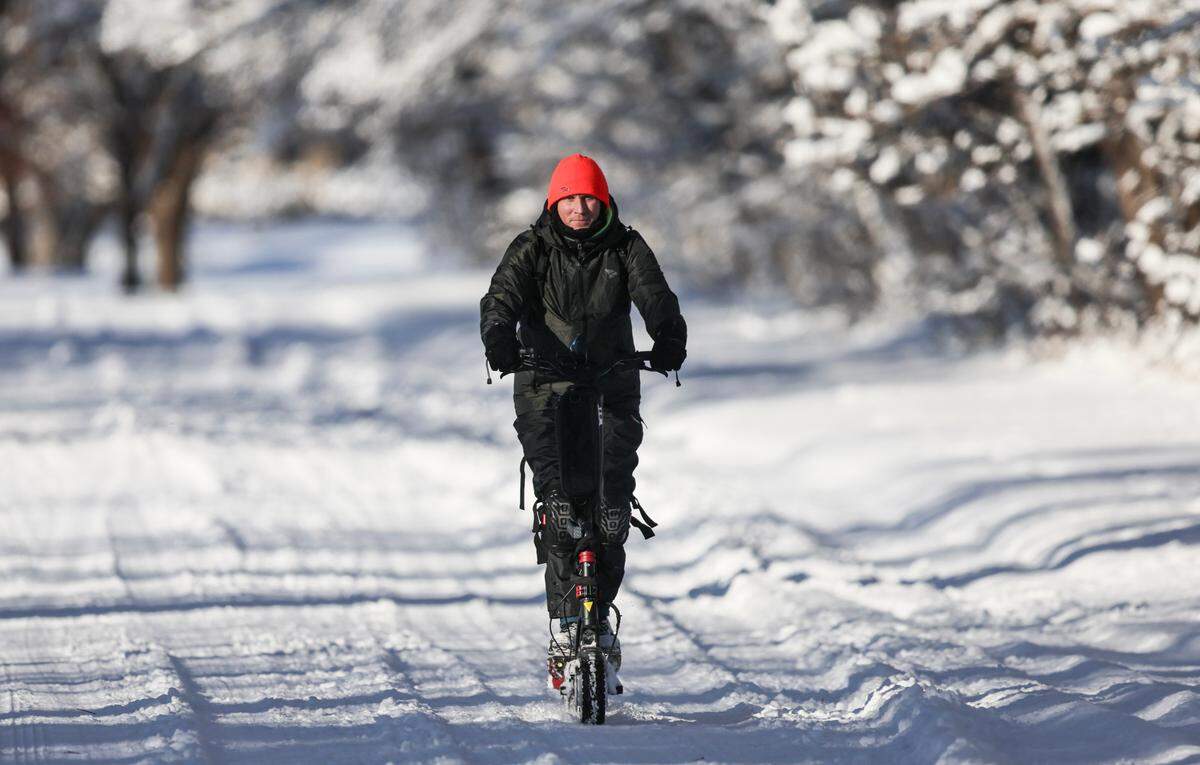 Will Kary rides an electric scooter through the snow along the southern edge of Oak Park on Friday morning. 