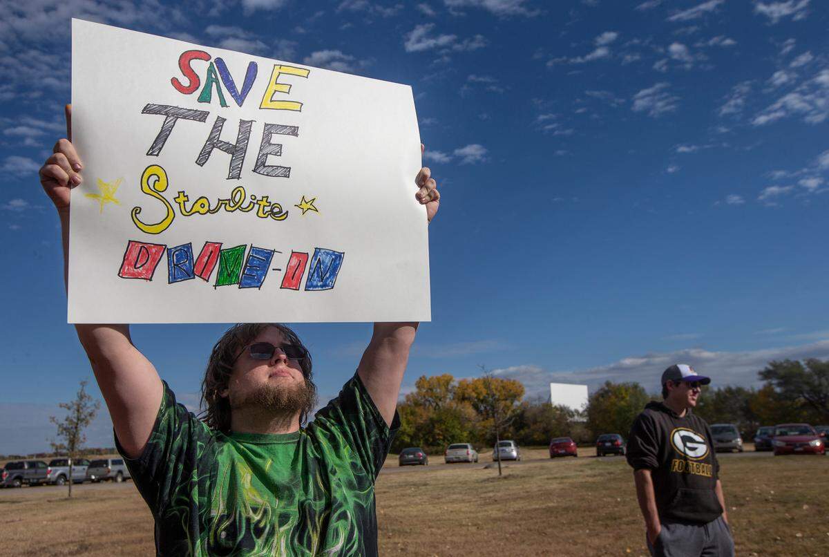 Jason Berg of Wichita holds of a sign during a rally to save the Starlite Drive-In at Chapin Park. The longtime Wichita business is slated to be sold for development. 