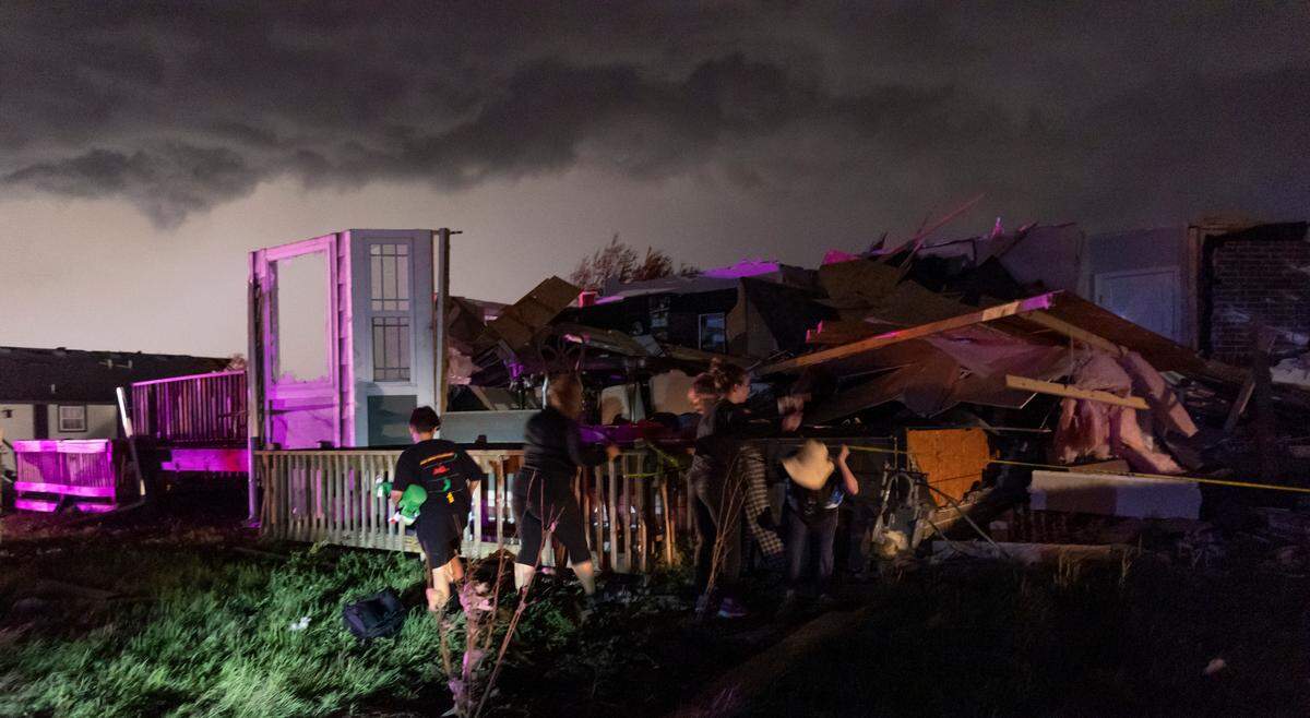 A family searches for belongings on east Minneha Ave. in Andover on Friday night after a tornado ripped through the area.