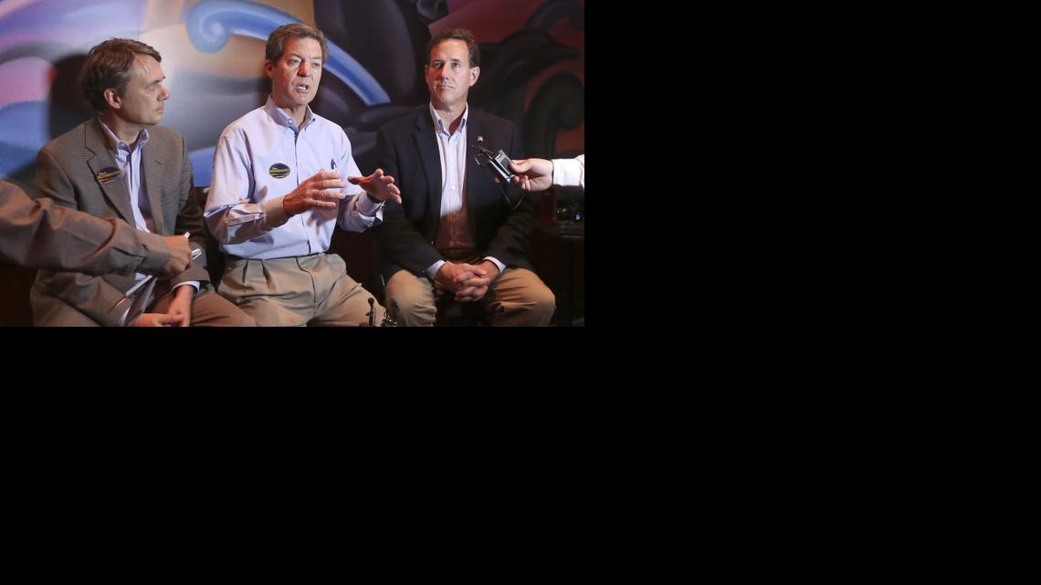 Kansas Gov. Sam Brownback, center, Kansas Lt. Gov. Jeff Colyer, left, and former Republican presidential candidate Rick Santorum during a news conference at the Warren Theatre East in Wichita. (July 14, 2014) 


