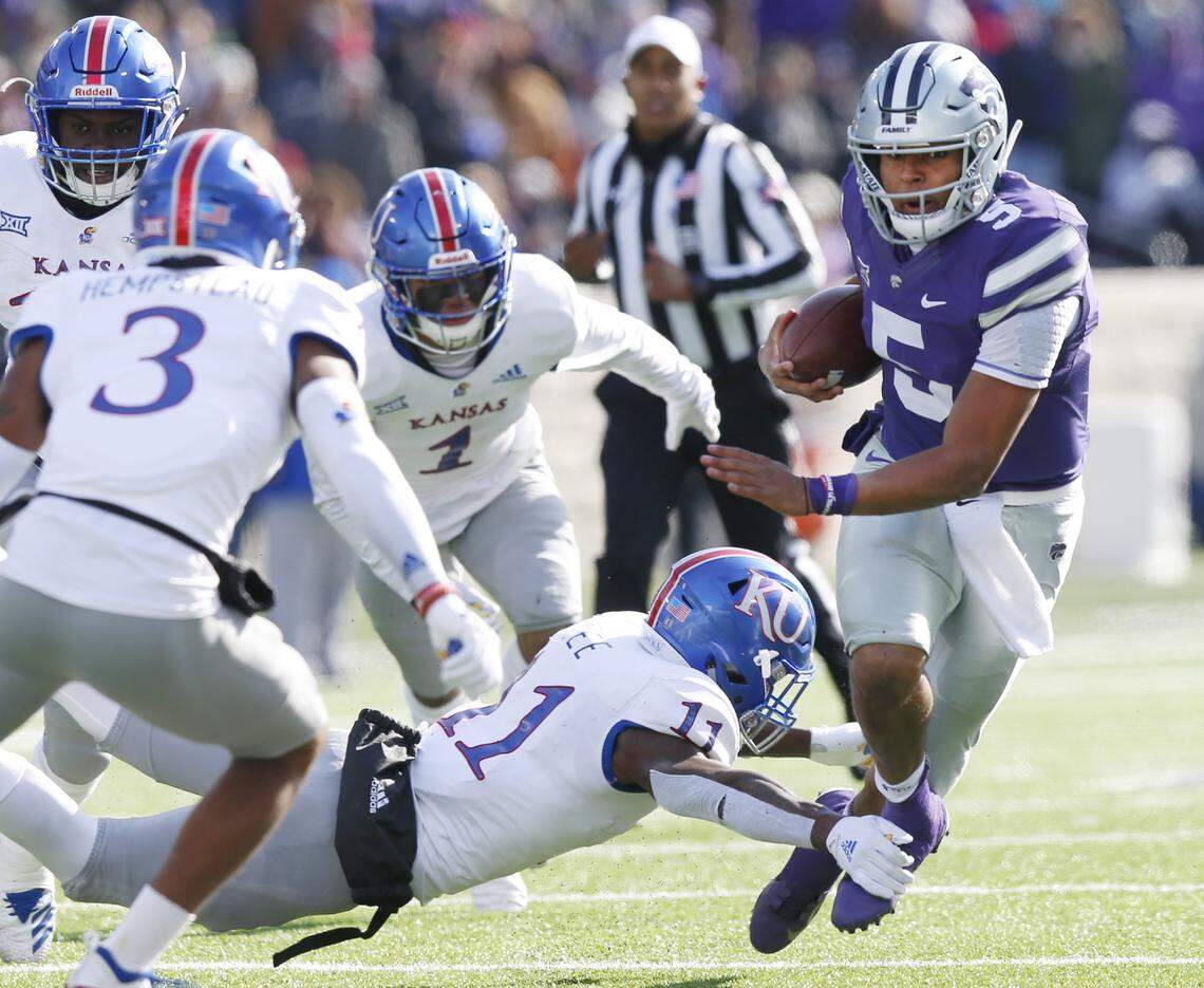 K-State quarterback Alex Delton, right, slips through the hands of Kansas safety Mike Lee Saturday in Manhattan.