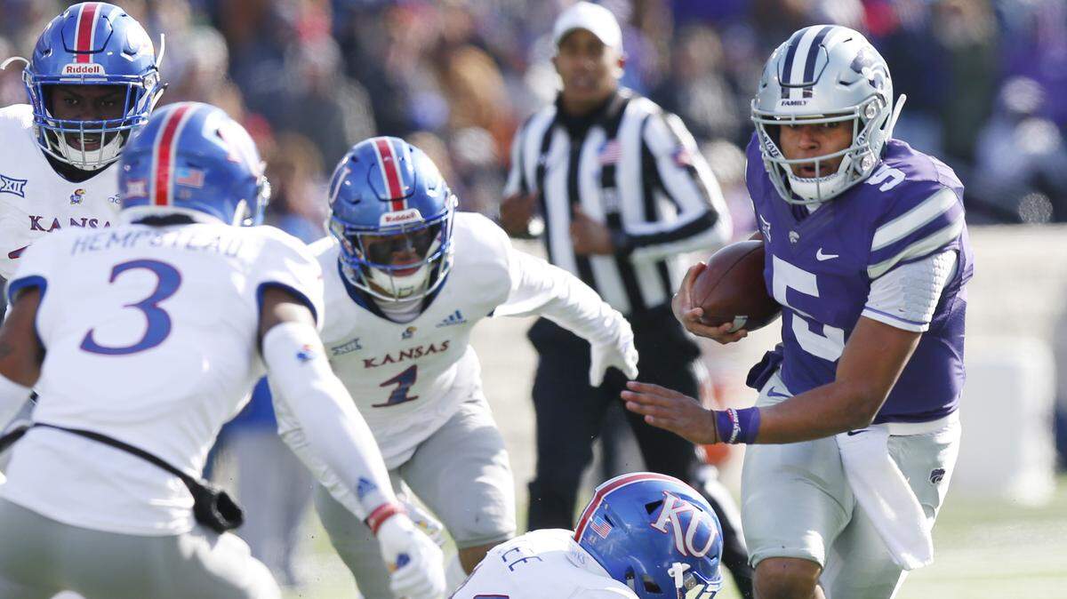 K-State quarterback Alex Delton, right, slips through the hands of Kansas safety Mike Lee Saturday in Manhattan.