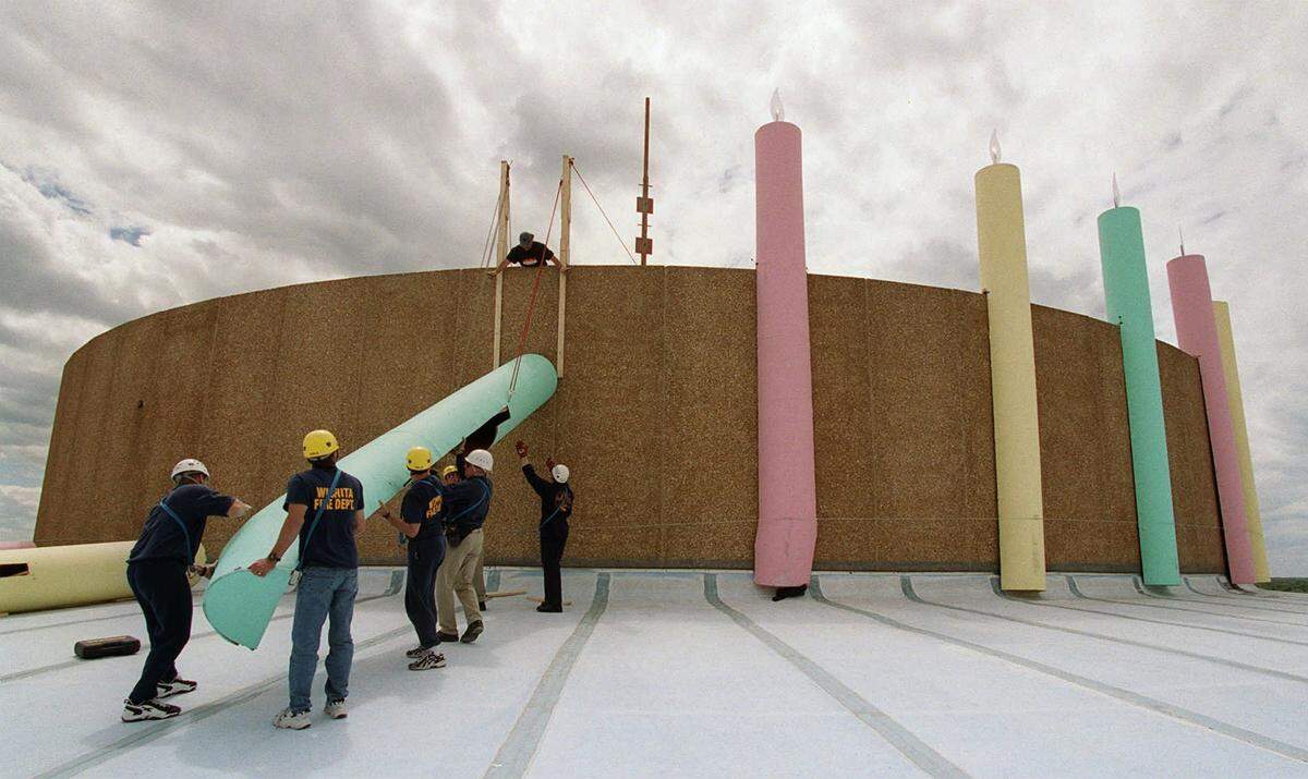 Century II workers and firefighters lift one of 30 candles to the top of Century II in 1999 when the building turned 30.