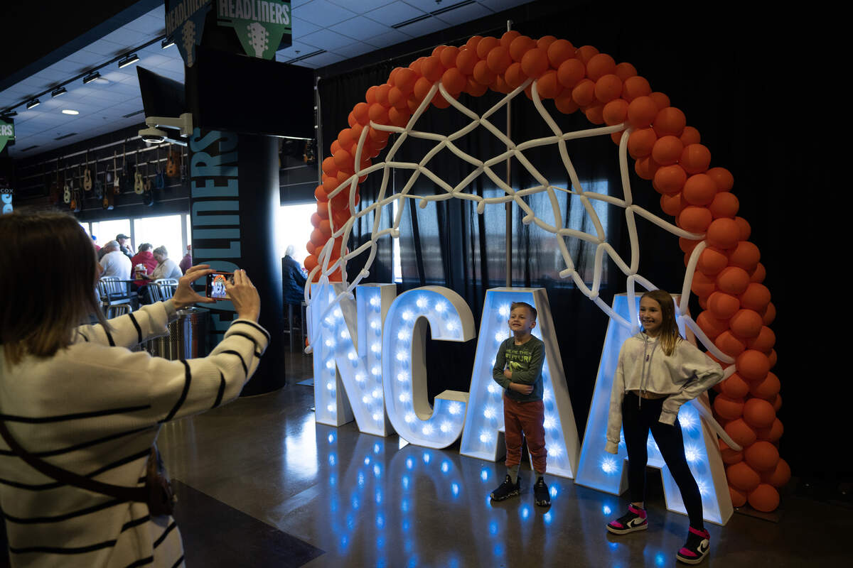 Fans pose in front of a NCAA sign on the concourse of INTRUST Bank Arena in the first round of the 2025 NCAA Division I Men’s Basketball Championship.
