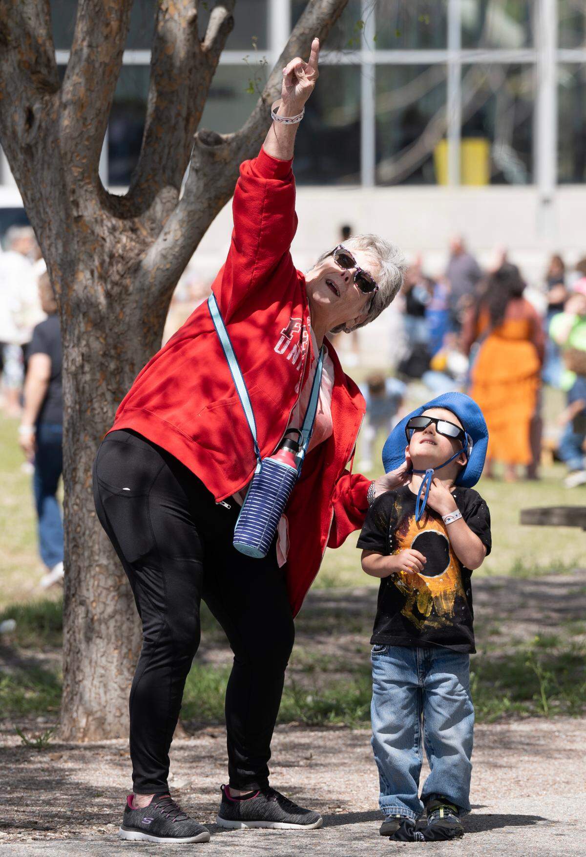 Kathy Slemp points to the sun to show her grandson Abram Gilmour during an eclipse party at Exploration Place on Monday.
