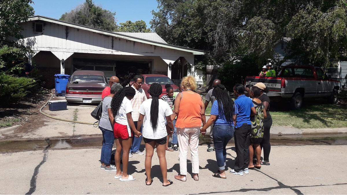 Bettie Clark-Johnson's family and friends pray in front of her north Wichita home on Friday morning seconds after learning that Wichita firefighters found a woman's body under a pile of debris Friday after battling a fire in Clark-Johnson's home.
