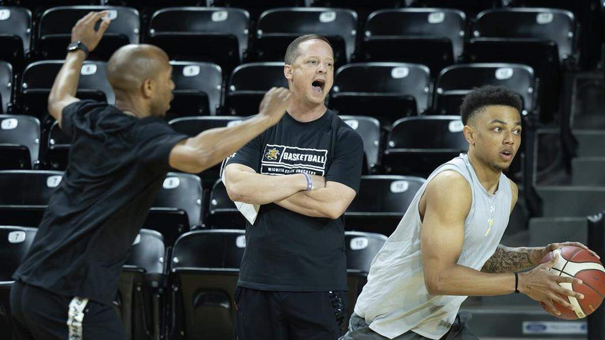 New Wichita State men’s basketball coach Paul Mills yells out instructions, while player Xavier Bell, right, participates in a drill.