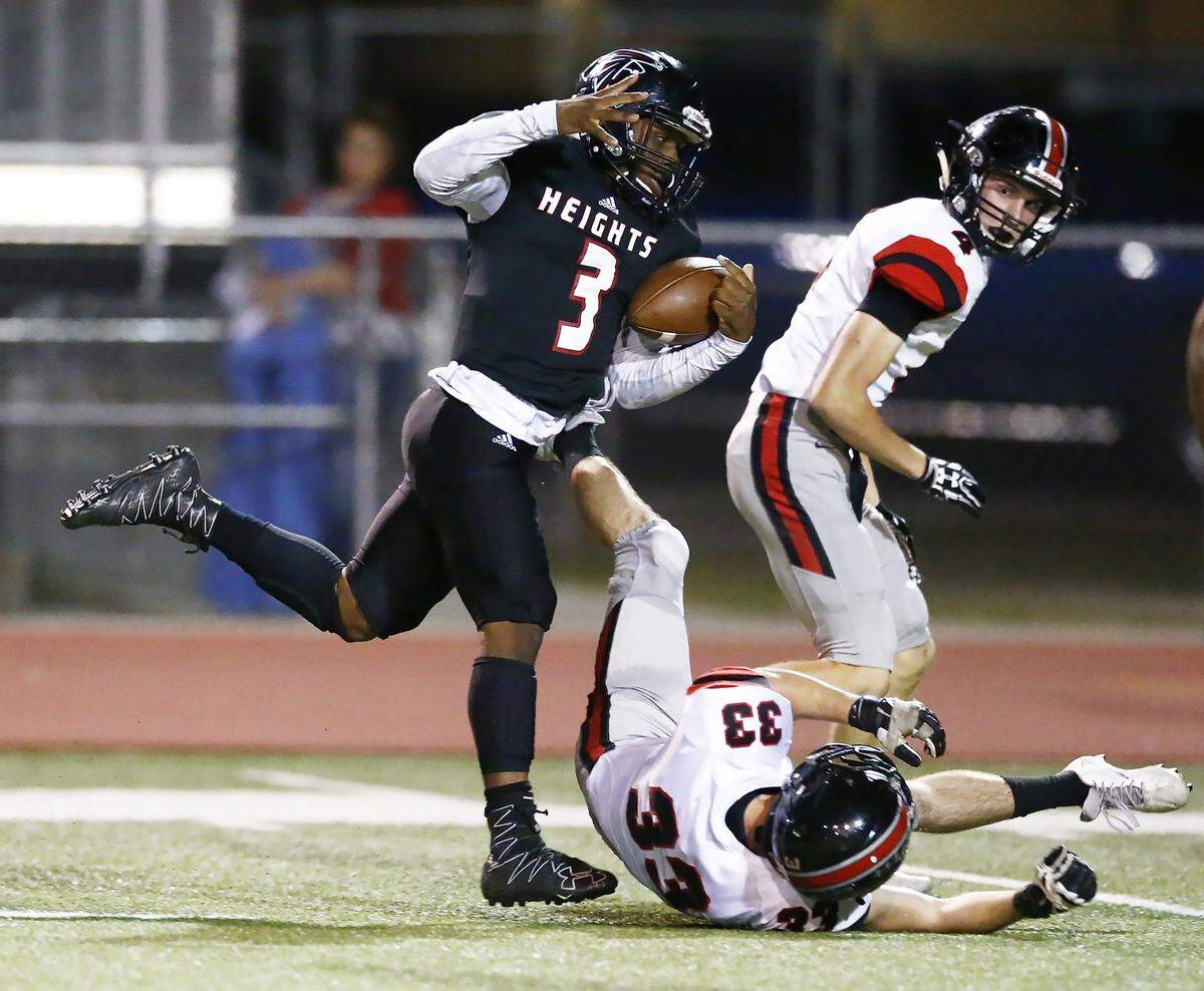 Heights quarterback K’Vonte Baker, left, tries to keep his balance during a first-half run against Emporia Friday night.