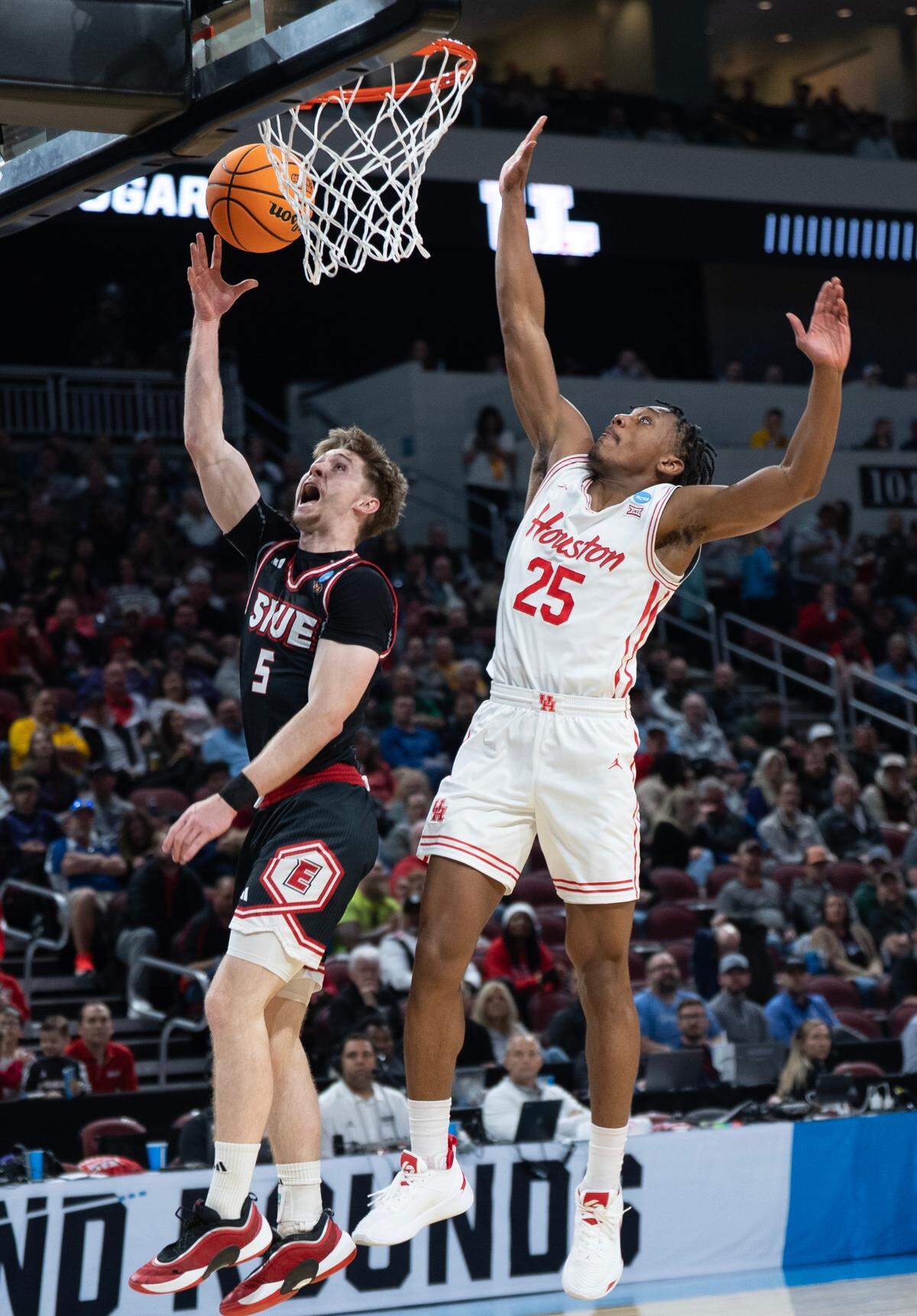 SIU-Edwardsville’s Declan Dillon shoots a missed layup in the first round of the 2025 NCAA Division I Men’s Basketball Championship.. Trailing him is Houston’s Mercy Miller.