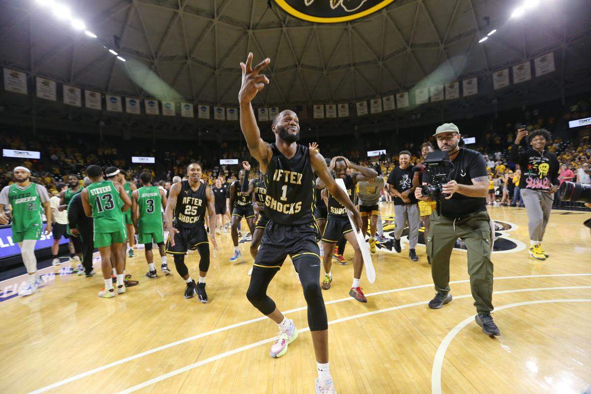 Markis McDuffie dances to place the AfterShocks banner on the tournament bracket wall after they won their second straight regional championship in The Basketball Tournament.