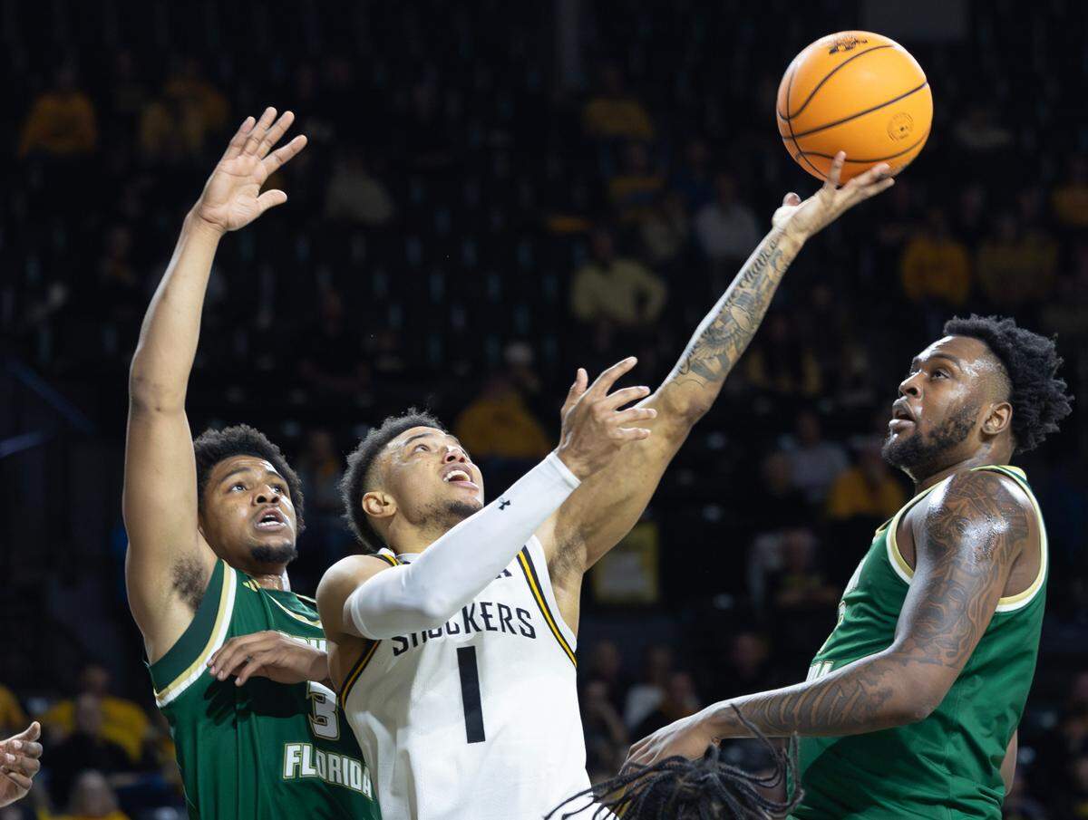 Wichita State’s Xavier Bell puts up a shot against South Florida’s Jimmie Williams, left, and Jamille Reynolds during the first half of their game on Monday night at Koch Arena.