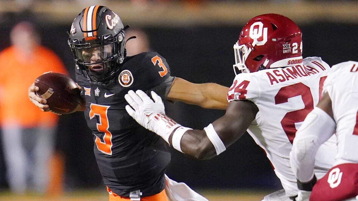 Oklahoma State quarterback Spencer Sanders (3) carries past Oklahoma linebacker Brian Asamoah (24) during the second half of an NCAA college football game Saturday, Nov. 27, 2021, in Stillwater, Okla. (AP Photo/Sue Ogrocki)