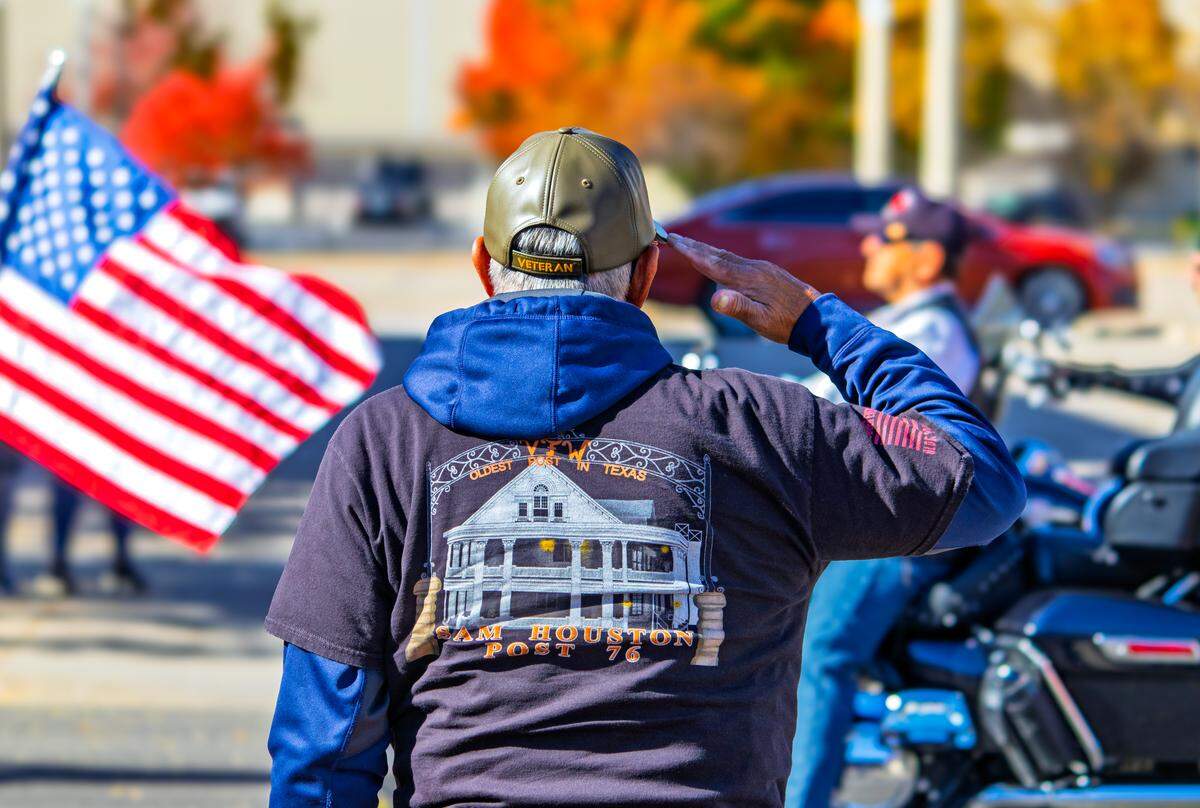 A veteran salutes as motorcyclists ride by with American flags during Wichita’s 2025 Veterans Day parade on Saturday, Nov. 8.