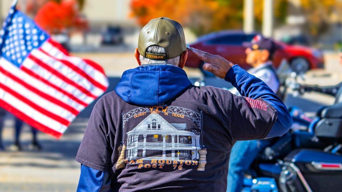 A veteran salutes as motorcyclists ride by with American flags during Wichita’s November 2025 veterans parade.