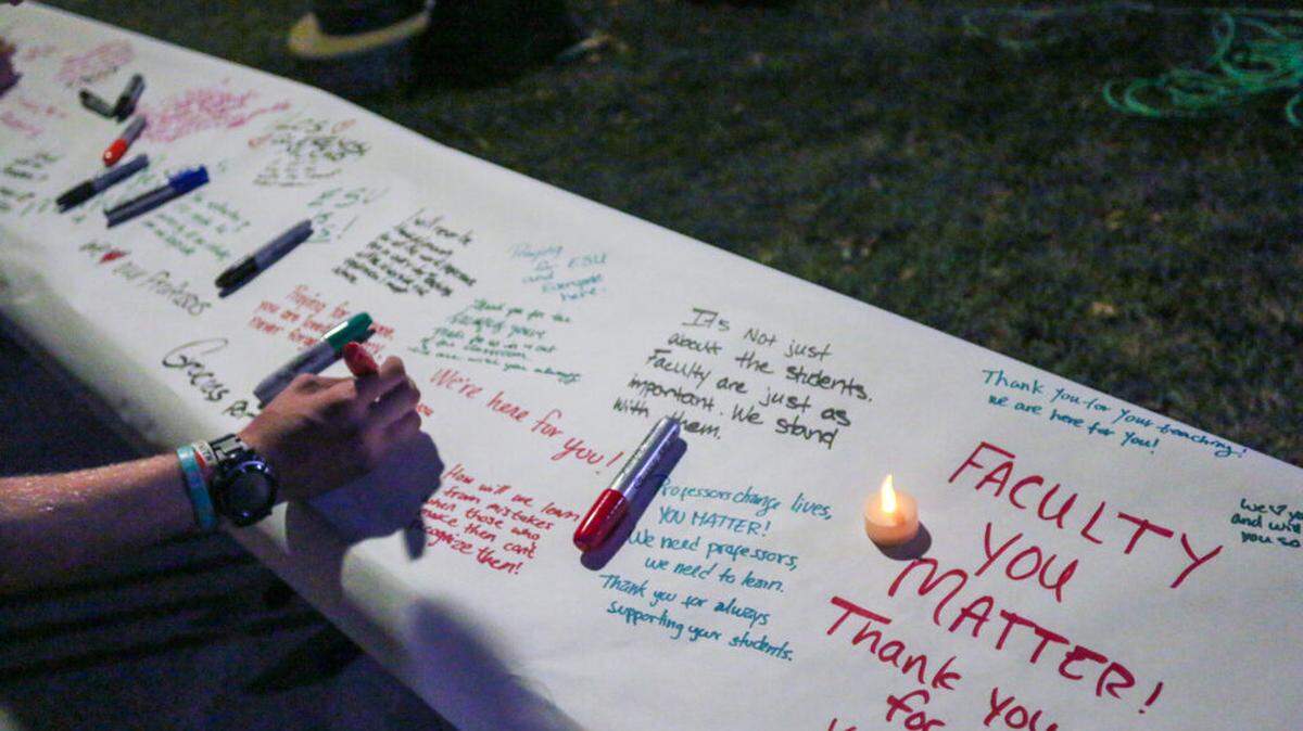 Emporia State students held a vigil and signed a paper roll supporting their professors, after 33 were laid off from the university a year ago.