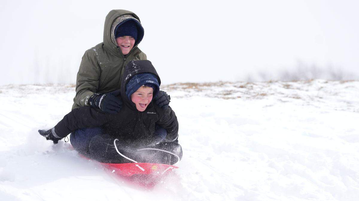 Twin brothers Gabriel and Elliot Morgan slide down a hill together at Linear Park in Goddard. Their father, Blake Morgan, promised his kids 10 minutes to play in the snow and extreme cold.