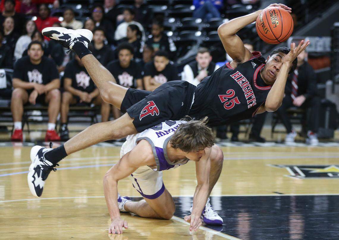 Heights’ Qyree Holtf falls over Blue Valley Northwest’s Michael Pauley during the second quarter of the 6A Championship game at Koch Arena on Saturday.