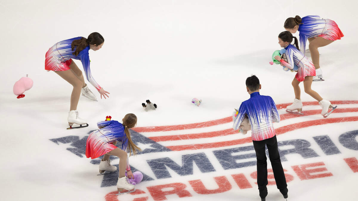 Stuffed animals are picked up off the ice after fans tossed them out after Amber Glenn’s performance in the women’s short program Thursday night at the U.S. Figure Skating Championships.