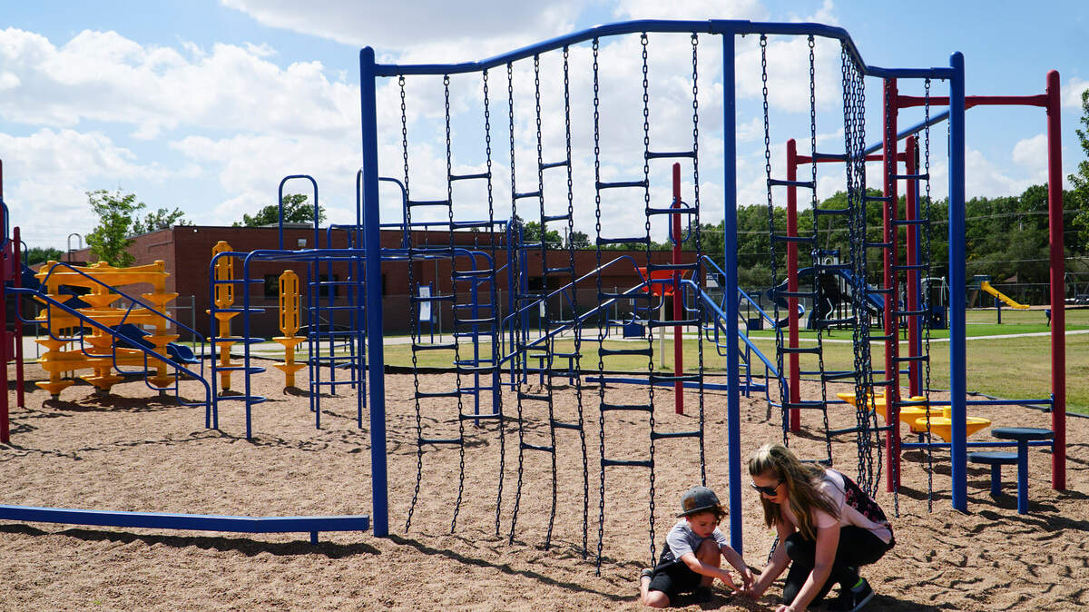 Abby Dedeaux and her 3-year-old son, Remy, play at the playground at Benton Elementary. Wichita school leaders approved a plan to fence off all elementary school playgrounds by the end of the year. (June 19, 2018)