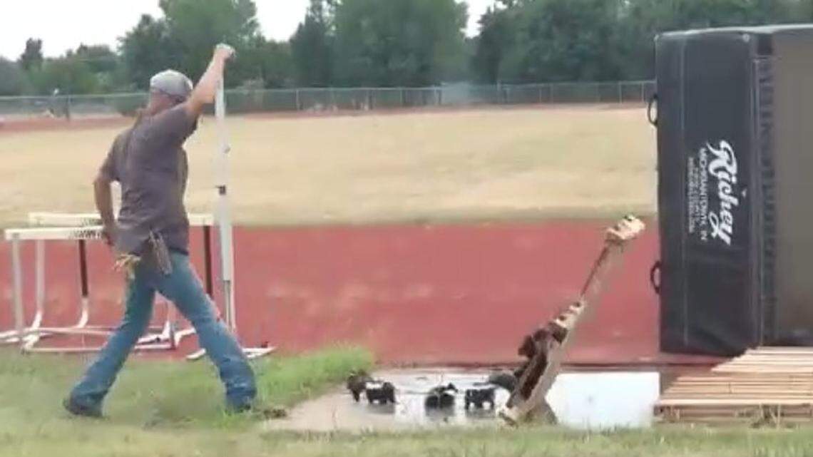 A Newton schools staff worker attempts to remove a wooden pallet that a group of skunks made a home out of over the weekend on the high school’s track field.