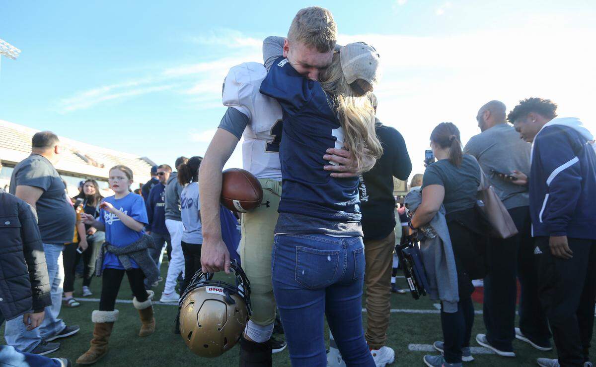 St. Thomas Aquinas quarterback Tate Raboin cries while being consoled by his mother after the Saints won the 5A state title over Wichita Northwest on Saturday in Pittsburg. 