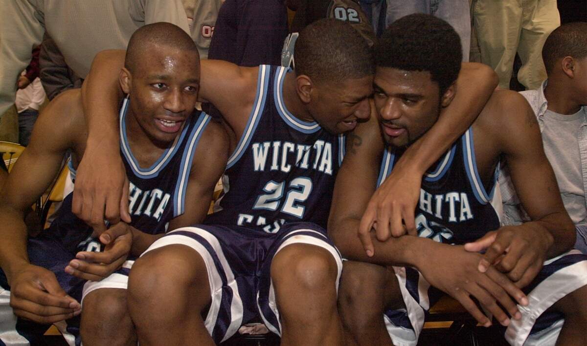 Wichita East’s Taj Gray, center, embraces teammates, Brandon Barrett, left, and Brent Freeman, right, following the win over Hutchinson for a state championship.