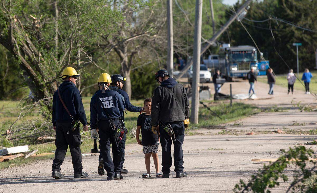 Wichita firefighters fist-bump 7-year-old Camden Oyewole while searing an area north of the Andover YMCA after a tornado hit it on April 29, 2022. Oyewole is a first-grader at Prairie Creek Elementary. (April 30, 2022)