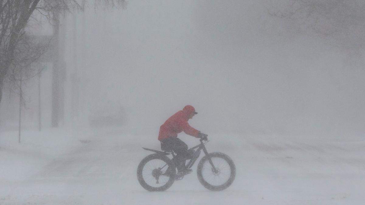 Michael Young braves blizzard conditions as he crosses First Street at Cleveland St. Young works at Bicycle X-Change on east Central and was on his way to work.