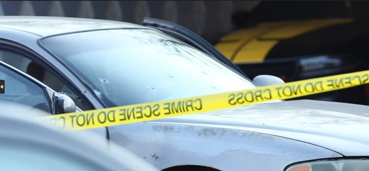 A car with apparent bullet holes in the front windshield was parked behind crime scene tape as Wichita detectives worked the scene of a shooting.