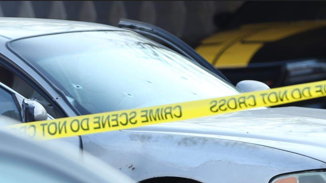 A car with apparent bullet holes in the front windshield was parked behind crime scene tape as Wichita detectives worked the scene of a fatal shooting in 2024.