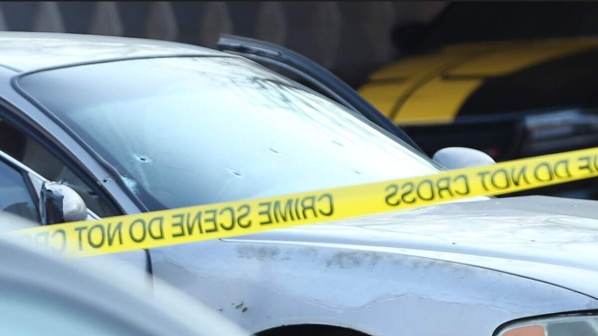 A car with apparent bullet holes in the front windshield was parked behind crime scene tape as Wichita detectives worked the scene of a fatal shooting in 2024.