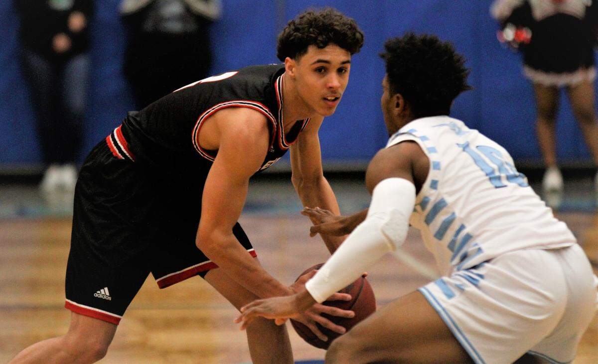 Wichita Heights senior Izaiah Hale scans the floor against Wichita East’s D’Ron Jacobs in the Falcons road win over the Aces on Wednesday night. (Jan. 2, 2019)