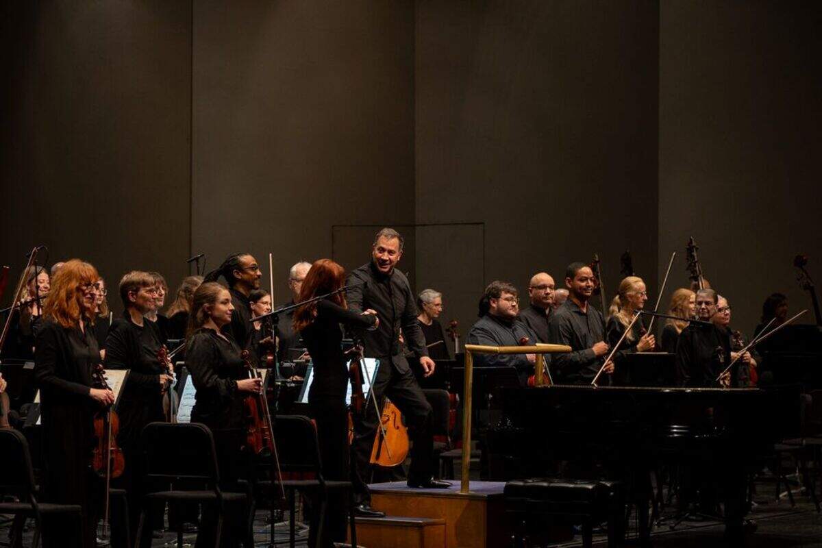 Music director Daniel Hege shakes the hand of concertmaster Holly Mulcahy.