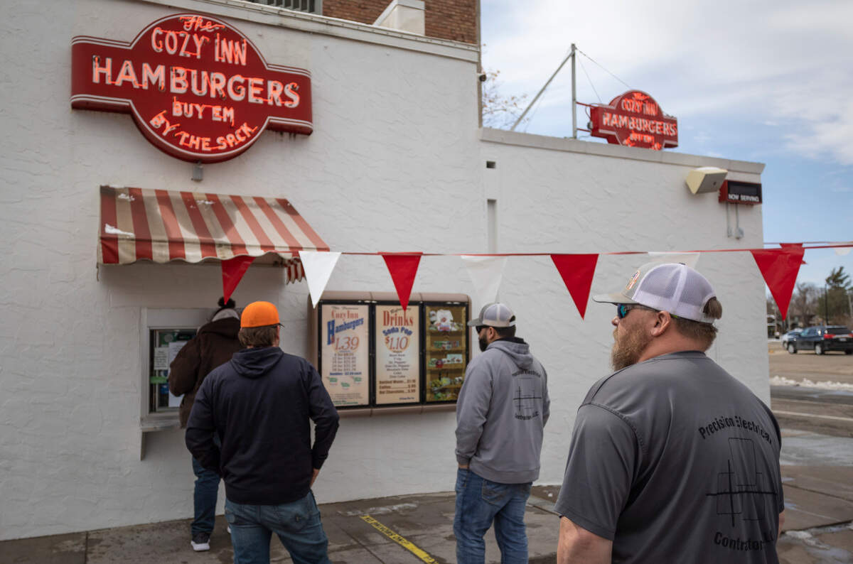 Customers wait for service outside a walk-up window at The Cozy Inn in Salina on Tuesday. The famous Kansas hamburger stand will celebrate their 100th anniversary this weekend.