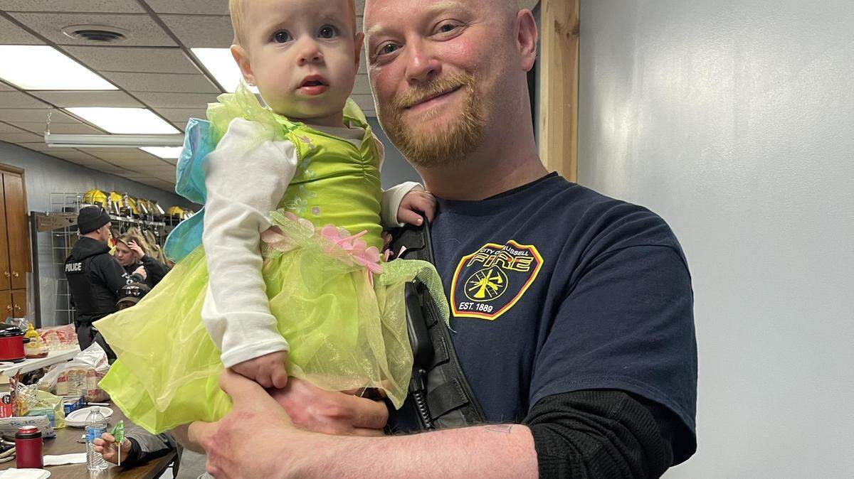 Russell fire chief Dylan Riedel poses for a photo with his niece during a trick-or-treat event at the fire department. Riedel was injured in an explosion while responding to a garage fire this summer. He has since returned to work.
