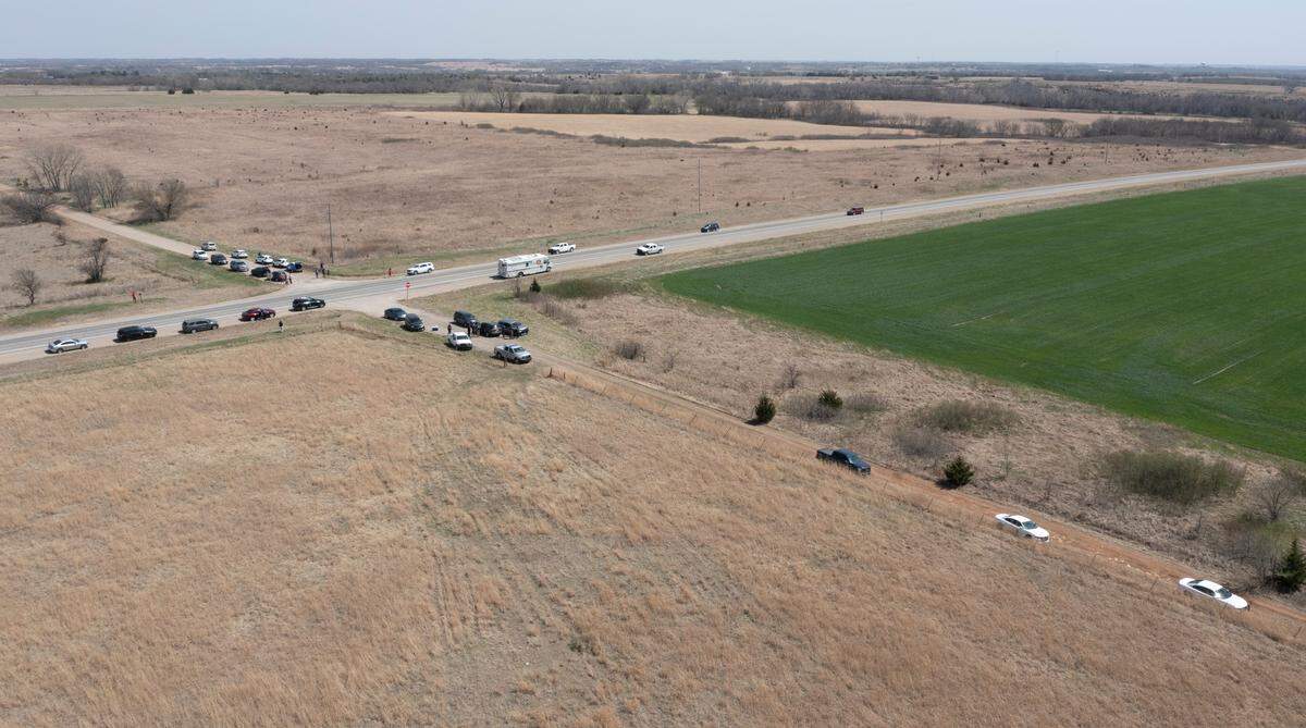 Law enforcement officers from several different agencies, along with members of the media, gather around the scene where three Cowley County sheriff’s deputies were shot and wounded on Friday north of Winfield. According to the Cowley County Sheriff’s Office, a suspect in the shootings was killed at the scene.