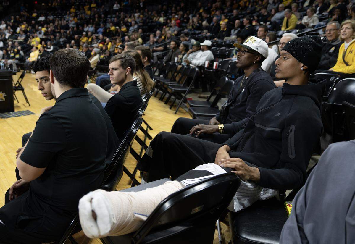 Wichita State’s Jaret Valencia watches the game against Rice behind the bench with his leg in a cast and propped up on a chair.