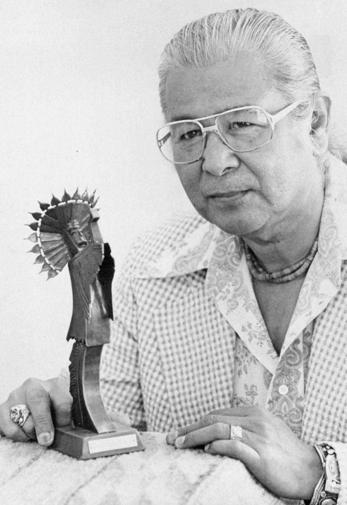 Blackbear Bosin poses with a miniature Keeper of the Plains statue.
