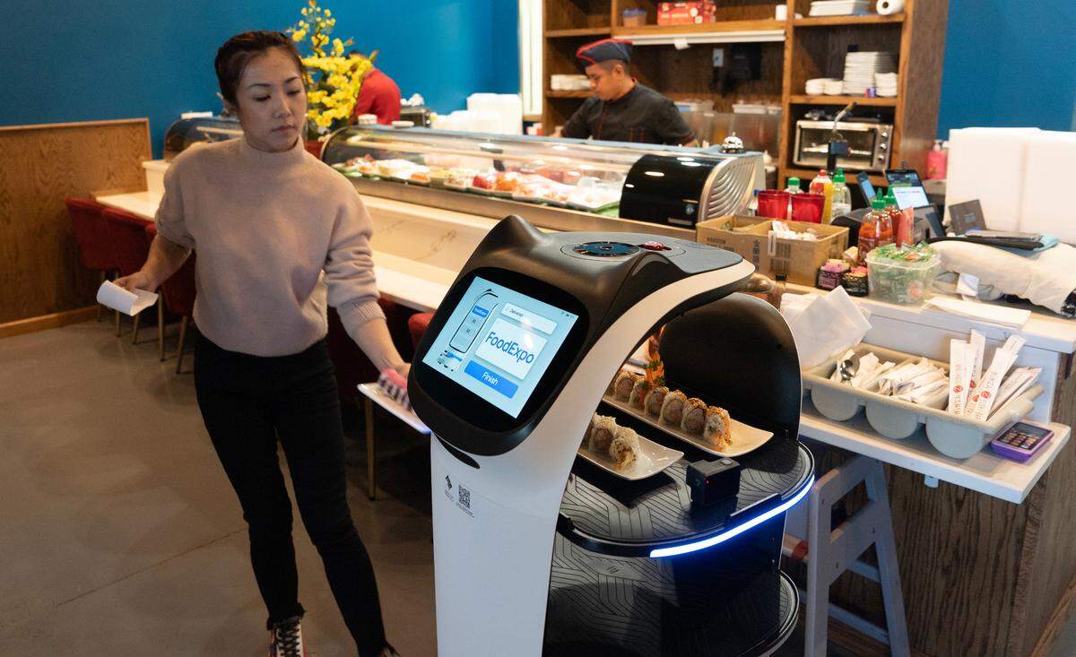 Ninza Sushi Bar owner Ada Yang loads food onto a robot at the restaurant’s new location at 13th and Tyler. The robot has a catlike face when it moves and delivers food to customers. The food usually is loaded and unloaded by the restaurant staff.