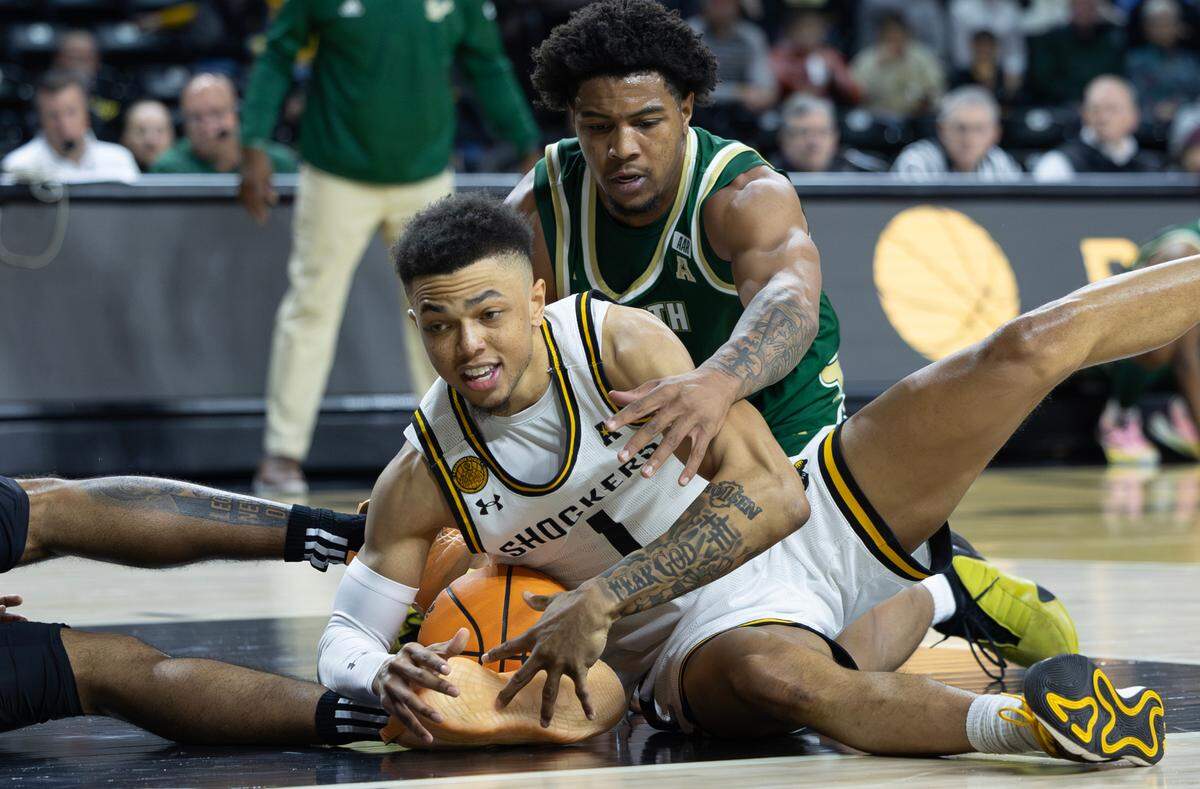 Wichita State’s Xavier Bell tries to keep control of loose ball against South Florida’s Jimmie Williams during the first half of their game on Monday night at Koch Arena.