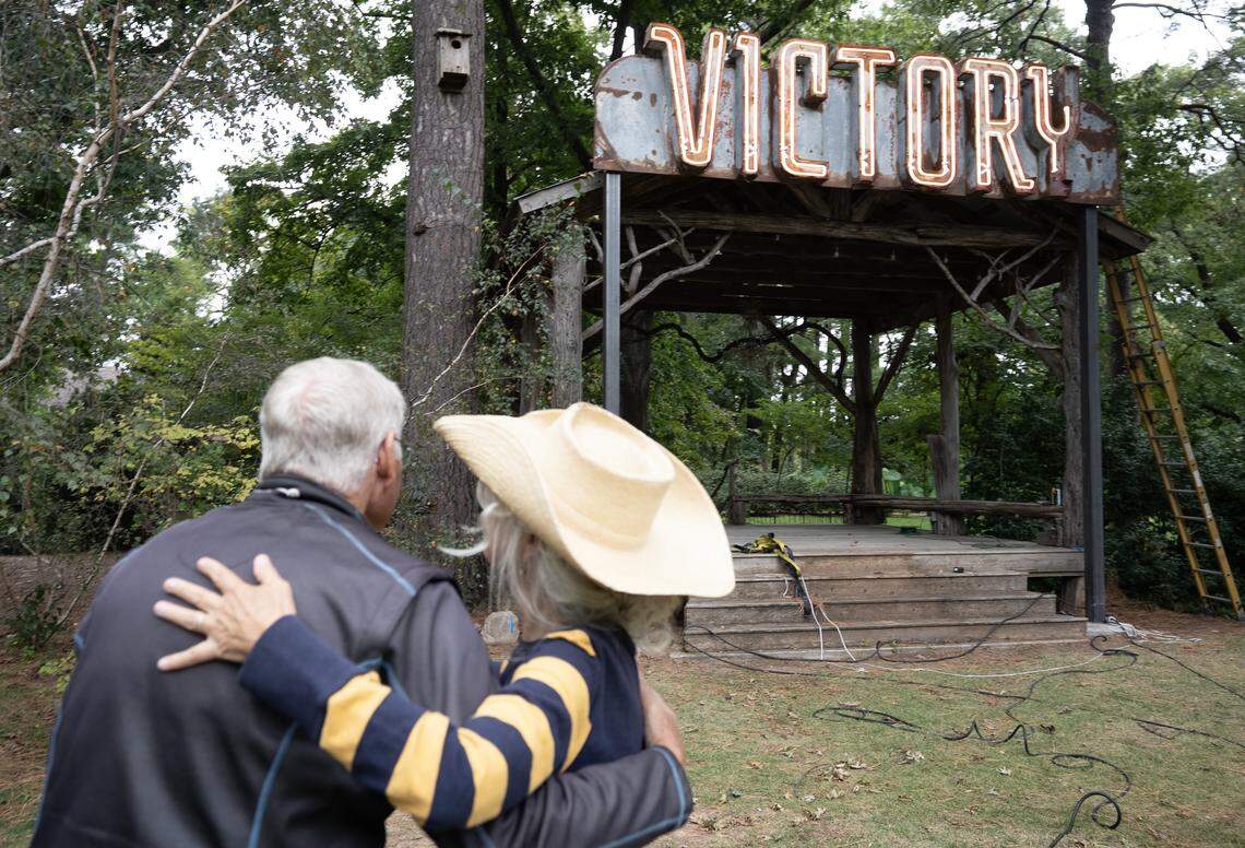Robin Macy, owner of the Bartlett Arboretum, hugs her friend Wes Marks after the historic Victory theater sign is installed over the arboretum’s Loblolly stage.