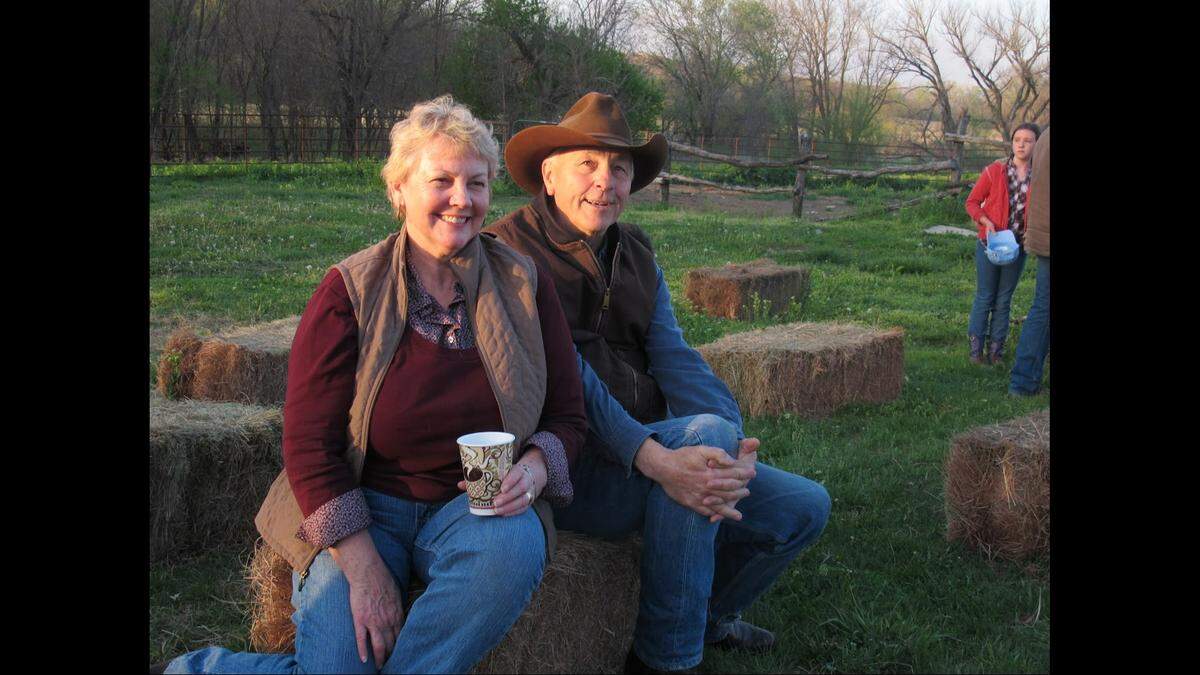 Jim Hoy and his wife, Catherine, smiling while sitting on a hay bale.