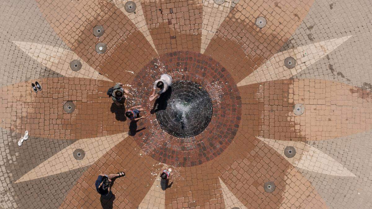 Children and adults play in the water fountain at Central Riverside Park on Thursday afternoon. The number of days over 100 degrees this year has been fewer than patterns in recent years.