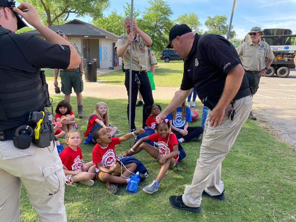A police officer bumps fists with a camper after the “Big Reveal” at the Boy Scout Awareness Camp on June 3, 2022 at OJ Watson Park. At the awareness camp, campers enjoyed a day of fun summer activities with their camp counselors. On the second day, their counselors were revealed to be first responders. The goal of the camp is to build connections between children and first responders.