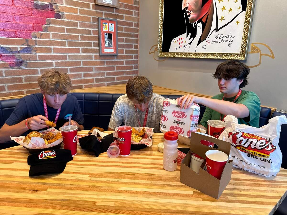 Friends and Tyrel Koehn, left, Elliott Hochstetler, center, and Landon Winn prepare to dig into their food. They three buddies from Whitewater were the first customers inside the new Raising Cane’s in Wichita.