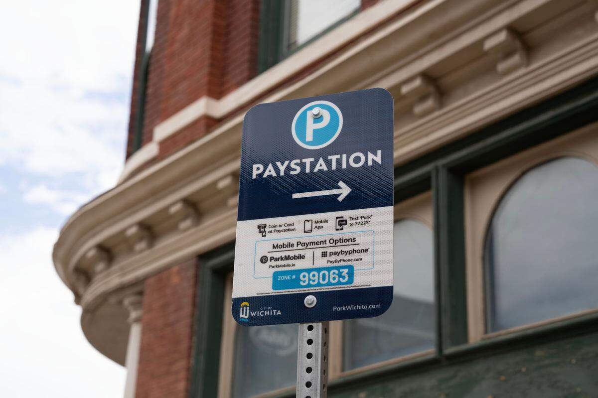 A sign at the corner of Douglas and Emporia points to a parking kiosk where drivers can pay for parking.