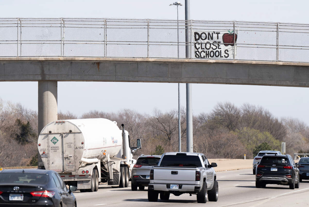 A sign that reads “Don’t Close Schools” hangs from the pedestrian walkway on Kellogg near Hillside before Monday night’s vote.