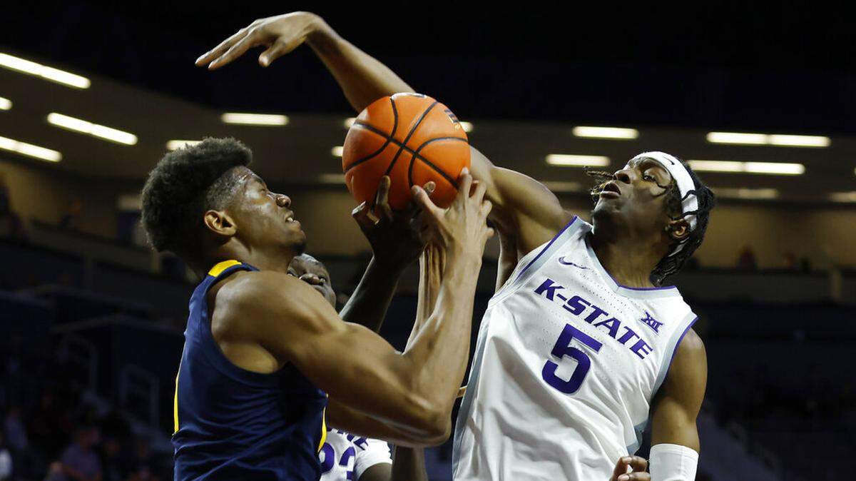 West Virginia forward Mohamed Wague, left, is blocked by Kansas State guard Cam Carter (5) as he attempts to score during the first half of an NCAA college basketball game, Saturday, Dec. 31, 2022, in Manhattan, Kan. (AP Photo/Colin E. Braley)