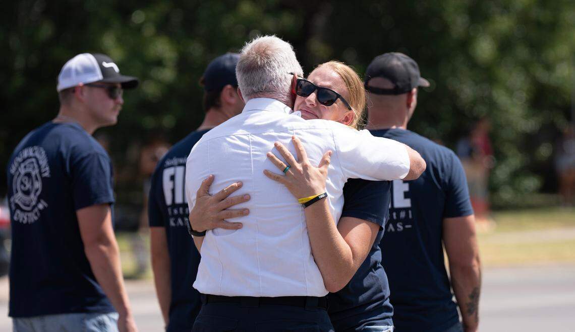 A Sedgwick County Firefighter hugs another firefighter moments before the procession for Wichita firefighter Ty Voth at Maple and 119th St. W. Voth, 27, collapsed suddenly and died while working on a house fire Thursday afternoon.